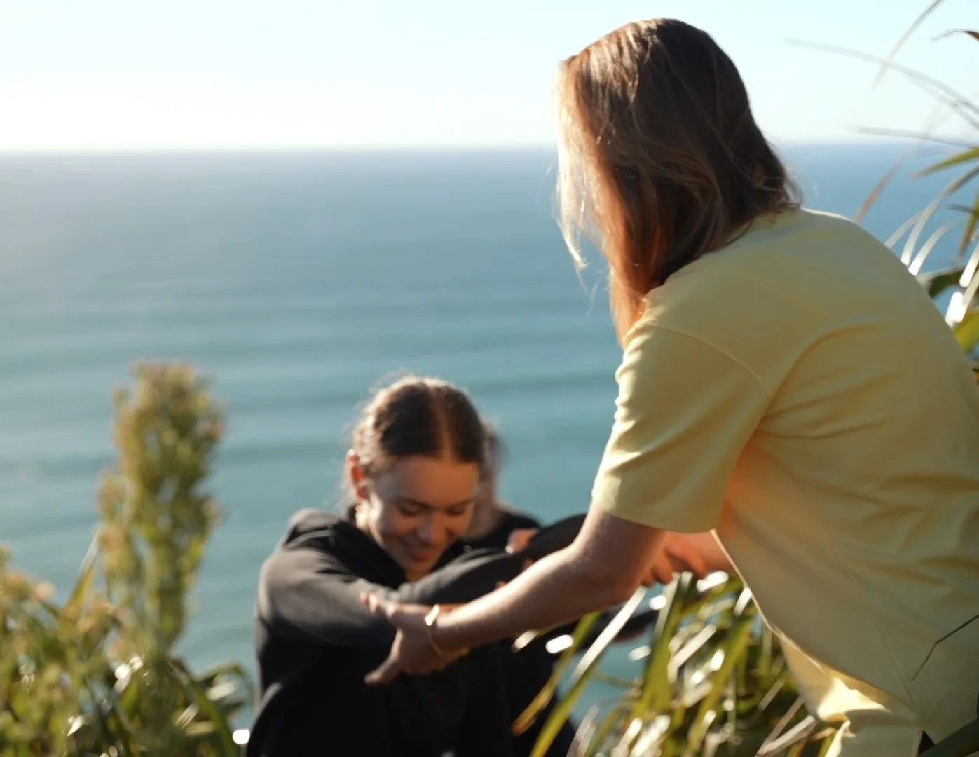 Two women supporting each other on a coastal path